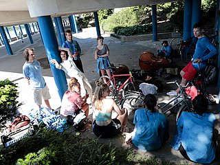 Gruppe Studierende mit Instrumenten und Fahrrädern stehen beisammen.