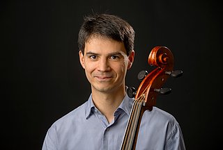 Prof. Viktor Töpelmann Es ist eine männliche Person im Portraitmodus zu sehen. Vor seiner Brust ist der Steg einer Viola da Gamba zu sehen.