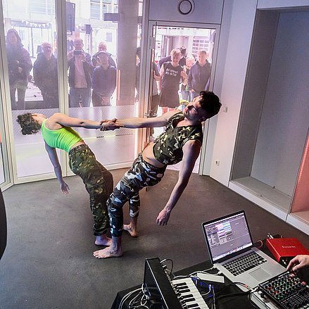 Final Celebration Zwei Tänzer*innen und ein DJ treten in einem verschlossen Raum vor Publikum auf