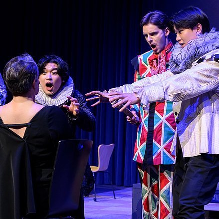 Ariadne auf Naxos - Richard Strauss Eine theatralische Szene mit fünf Darstellenden in barocken Kostümen – dramatische Gesten und Mimik richten sich auf eine sitzende Figur im Vordergrund.