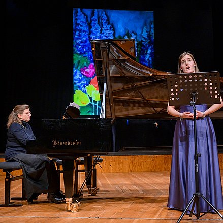 Eine Person sitzt am Flügel und eine weitere Person singt